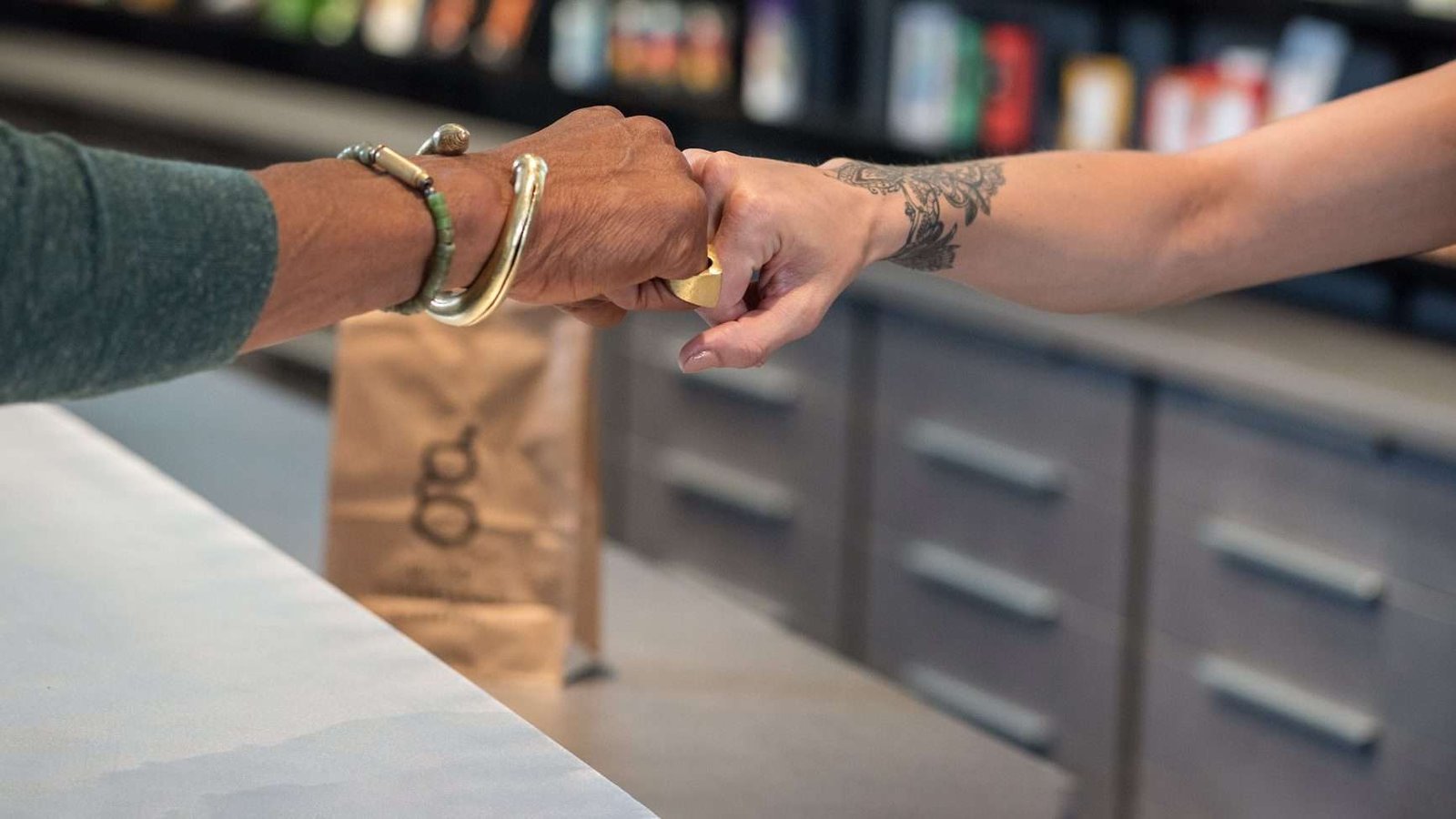 Two people sharing a friendly fist bump inside a Good Chemistry store